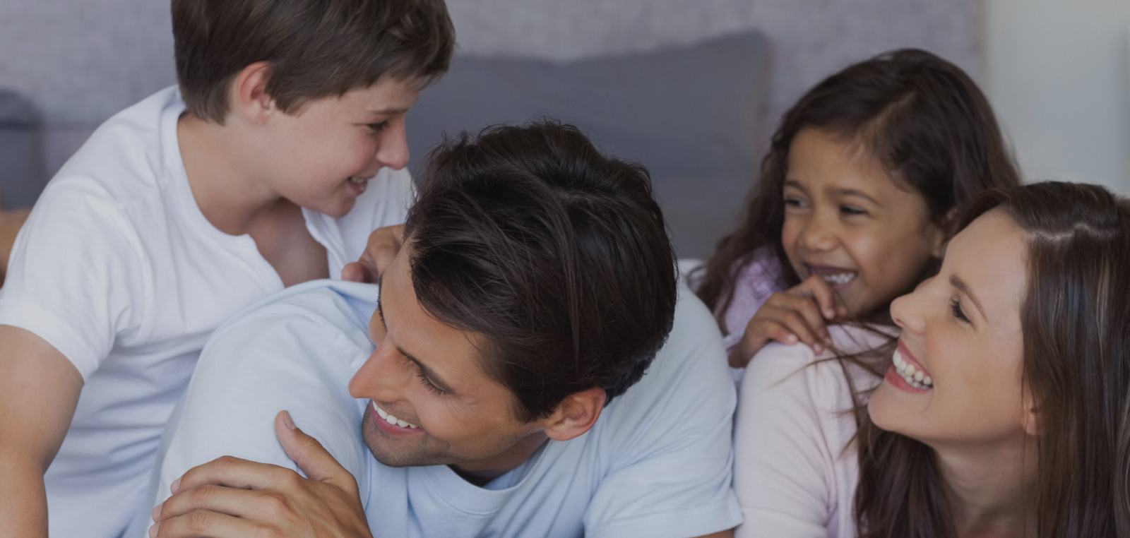 family smiling on bed